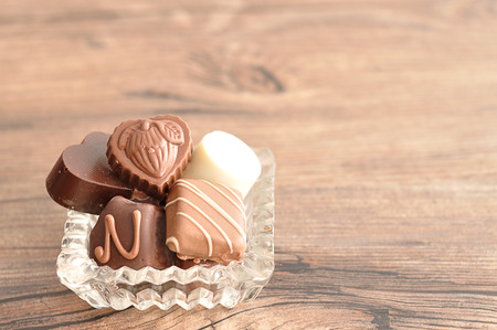 A variety of chocolates displayed in a fancy glass containerの写真素材