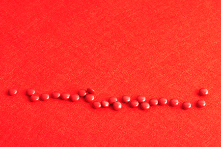A row of red pills on a red backgroundの写真素材