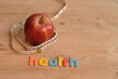 A red apple displayed with a measuring tape and the word healthの写真素材