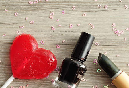 Black nail polish and lipstick displayed with a red heart shape lollipopの写真素材
