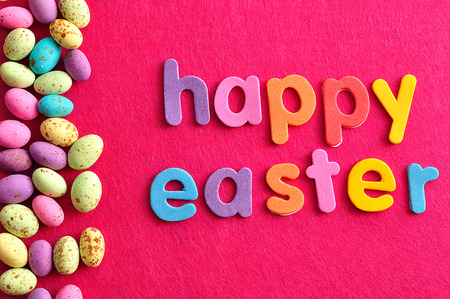 The words happy easter displayed with speckled easter candy eggs on a pink background
