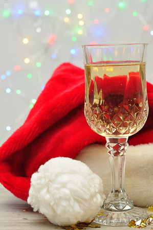 A glass of champagne displayed with a Santa hat and out of focus lightsの写真素材
