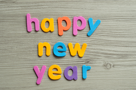 Happy new year in colorful letters on a wooden backgroundの写真素材