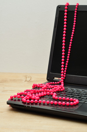 An open laptop with a string of pink beadsの写真素材