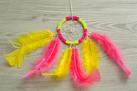 A dream catcher made out of pink and yellow feathersの写真素材