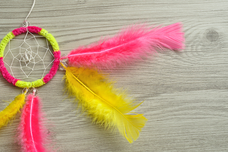 A dream catcher made out of pink and yellow feathersの写真素材
