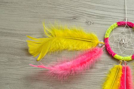 A dream catcher made out of pink and yellow feathersの写真素材