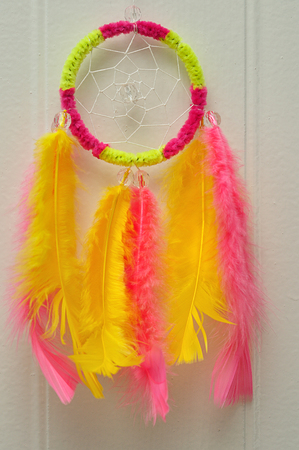 A dream catcher made out of pink and yellow feathersの写真素材