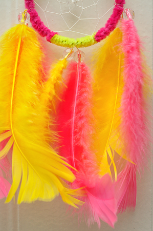 A dream catcher made out of pink and yellow feathersの写真素材