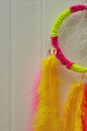 A dream catcher made out of pink and yellow feathersの写真素材