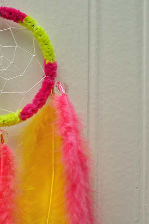A dream catcher made out of pink and yellow feathersの写真素材