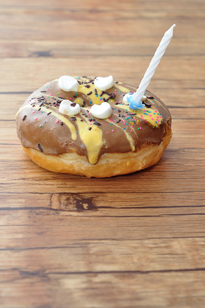 A colorful doughnut with a white birthday candleの写真素材