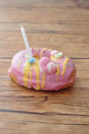 A colorful doughnut with a white birthday candleの写真素材