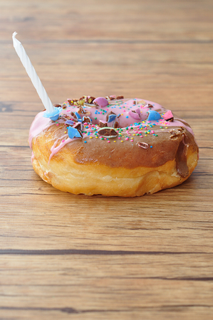 A colorful doughnut with a white birthday candleの写真素材