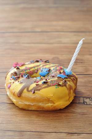 A colorful doughnut with a white birthday candleの写真素材