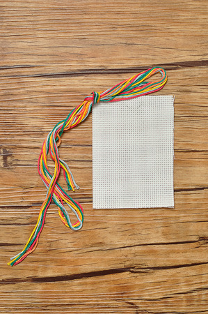 String of colorful embroidery thread displayed with a piece of embroidery fabricの写真素材