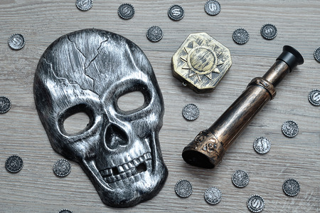 A skull mask, compass and an eyeglass with toy pirate coinsの写真素材