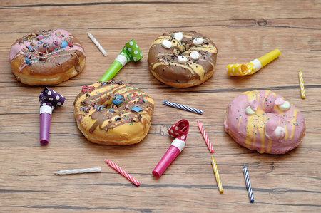 Doughnuts displayed with birthday candles and party blowersの写真素材