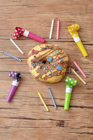 A doughnut displayed with birthday candles and party blowersの写真素材