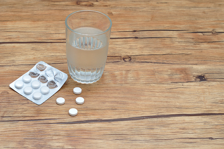 White pills displayed with a glass of water and a blister packの写真素材