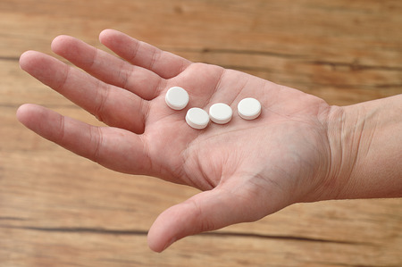 A womanâs hand holding small white pillsの写真素材