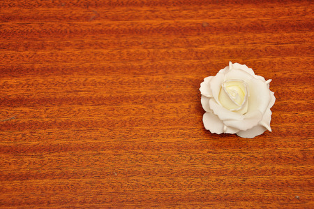 A white artificial rose against a wooden backgroundの写真素材