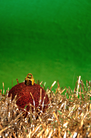 A single Red Christmas bauble with silver tinsel against a green backgroundの写真素材