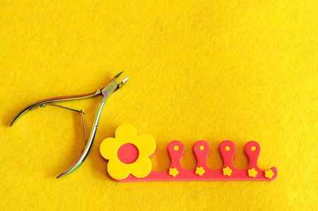 Nail clipper and toe separator on a yellow backgroundの写真素材