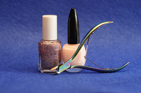 Nail polish and a nail clipper on a blue backgroundの写真素材