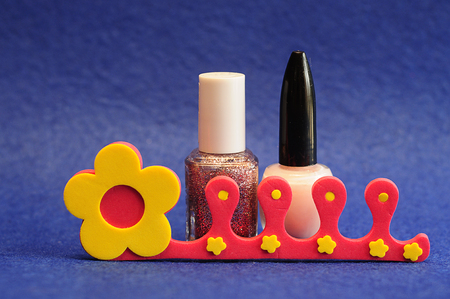 Nail polish and a toe separator on a blue backgroundの写真素材