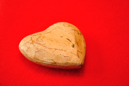 A wooden heart isolated against a red backgroundの写真素材
