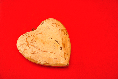A wooden heart isolated against a red backgroundの写真素材