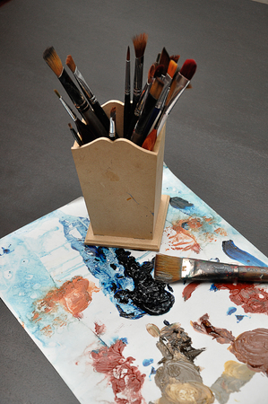 Splashes of paint with a paintbrush on a white background and a container filled with paint brushesの写真素材