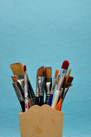 A collection of different size paint brushes in a wooden containerの写真素材