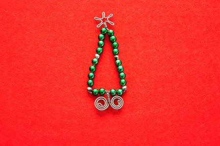 A christmas tree made out of beads and wire on a red backgroundの写真素材