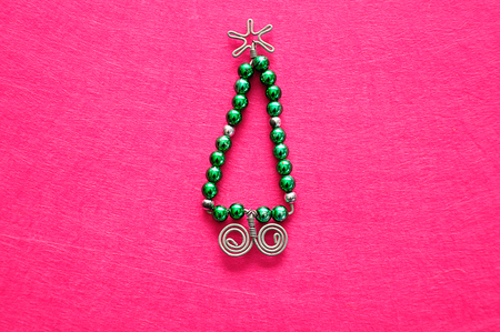 A christmas tree made out of beads and wire on a pink backgroundの写真素材
