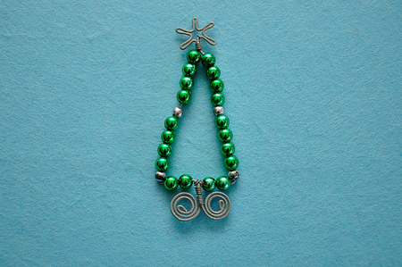 A christmas tree made out of beads and wire on a blue backgroundの写真素材