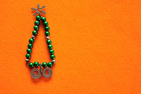 A christmas tree made out of beads and wire on an orange backgroundの写真素材