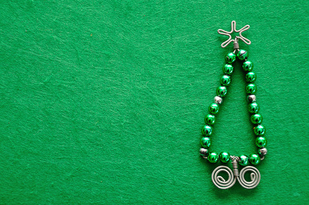 A christmas tree made out of beads and wire on a green backgroundの写真素材