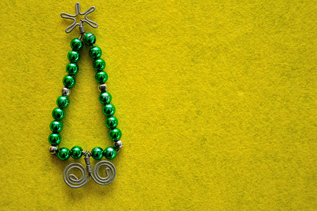 A christmas tree made out of beads and wire on a yellow backgroundの写真素材
