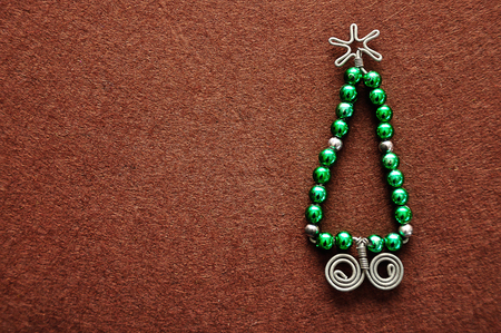 A christmas tree made out of beads and wire on a brown backgroundの写真素材