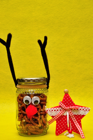 A jar decorated as a reindeer filled with pretzels and a red starの写真素材