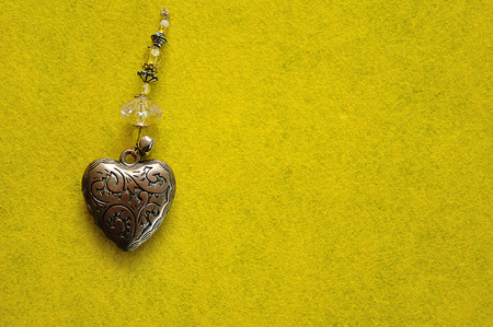 A decorated steel heart on a yellow backgroundの写真素材