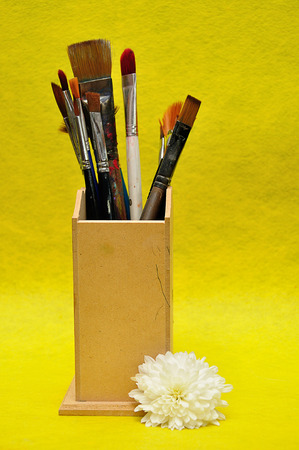 A collection of different size paint brushes in a wooden container with a white asterの写真素材