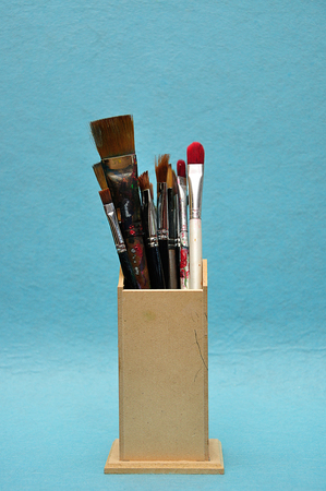 A collection of different size paint brushes in a wooden containerの写真素材