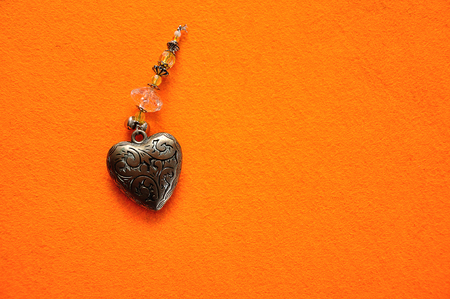 A decorated steel heart on an orange backgroundの写真素材