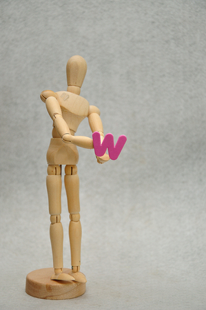 A wooden mannequin holding a letter wの写真素材