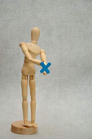 A wooden mannequin holding a letter xの写真素材
