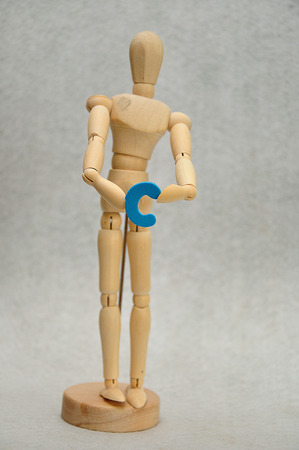 A wooden mannequin holding a letter cの写真素材