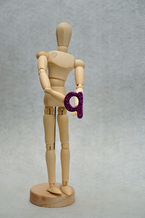 A wooden mannequin holding a letter qの写真素材